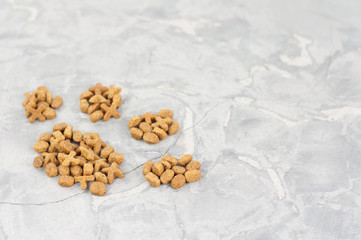 Footprint laid out of dry brown cat food on old gray concrete floor