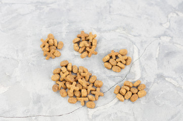 Footprint laid out of dry brown cat food on old gray concrete floor