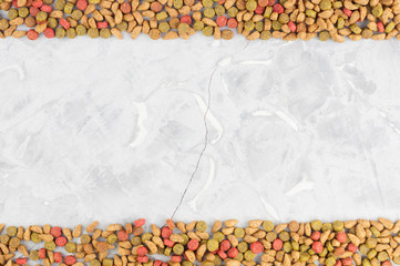 Two line of dry coloured cat food scattered on old gray concrete floor