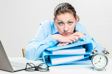A frustrated and tired accountant with folders works at night in the reporting period