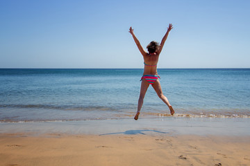 Fototapeta na wymiar Jumping woman at the beach