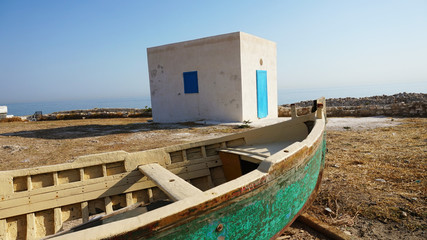 Fototapeta na wymiar Old boat and white hut on beach with door and window blue