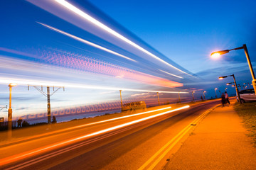 Obraz premium Light trails of a vehicle from the side of a road during dusk