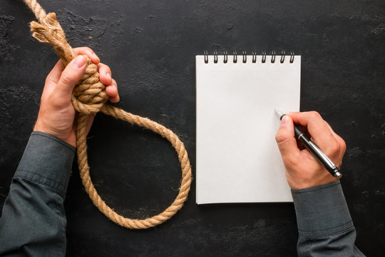 A man writes a suicide note and holds a rope loop