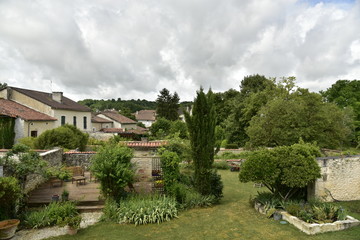 Fototapeta na wymiar Jardins et maisons rustiques sous un ciel gris au village de Champagne ,au Périgord Vert