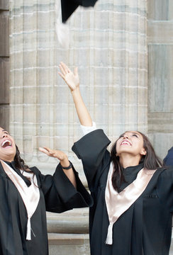 Happy and excited female graduates throwing hats in the air