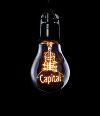 Hanging lightbulb with glowing Capital concept.