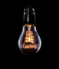 Hanging lightbulb with glowing Coaching concept.