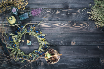 Dried branches, leaves, a wreath on an old wooden countertop. Candle, cones and jars with colored salt.