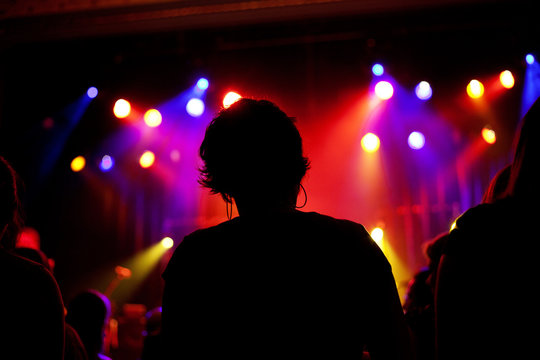 Silhouette of girl with short hair and hoop earrings at a concert