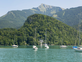 Naklejka premium Small harbor in Wolfgang see mountain lake. Anchored yachts, sunny weather. Summer sailing in Alps. Sport hiking landscape background.