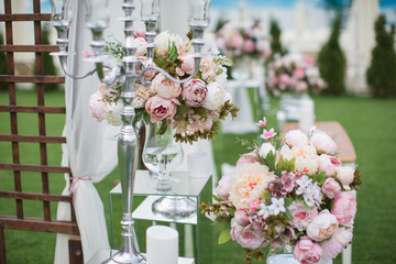 Outdoors wedding decoration with flower bouquets, candles and garlands
