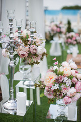 Outdoors wedding decoration with flower bouquets, candles and garlands
