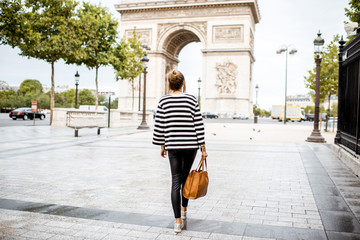 Lifestyle portrait of a young stylish business woman walking outdoors near the famous triumphal...