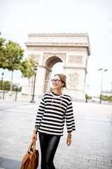 Lifestyle portrait of a young stylish business woman walking outdoors near the famous triumphal arch in Paris