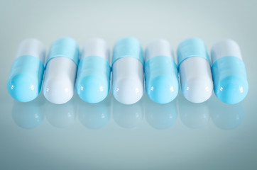 Pharmacy theme. A row of Blue and White Isolated Capsules on the White Surface. Closeup.