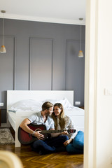 Obraz premium Romantic pair playing guitar on floor