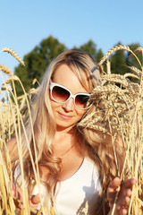 Молодая светловолосая девушка в солнцезащитных очках на пшеничном поле

