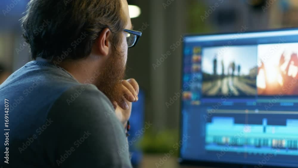 Poster male video editor works with footage and sound on his personal computer with two displays. he works 