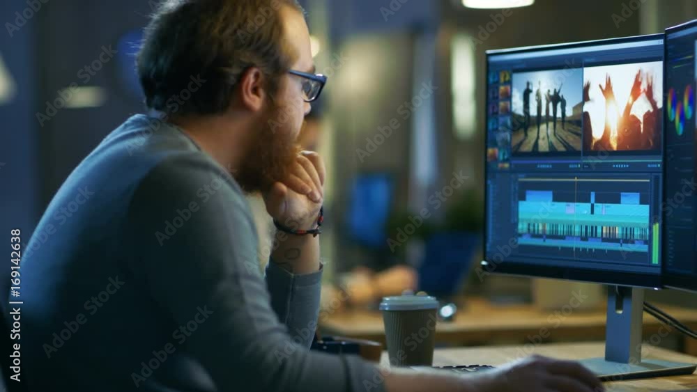 Poster male video editor works with footage and sound on his personal computer with two displays. he works 