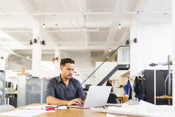Young mixed race designer working in his spacious office