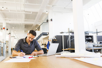 Young mixed race designer working in his spacious office