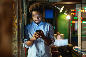 Young entrepreneur using his phone in a creative office.