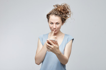 Beautiful stylish young Caucasian female student having surprised expression after receiving message looking with big opened eyes and finger on her mouth being happy to pass exam. Suddenness concept.