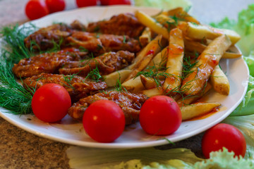 Chicken ribs in honey sauce with French fries and vegetables.