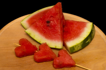 slices of watermelon, heart on wooden background