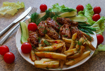 Chicken ribs in honey sauce with French fries and vegetables.