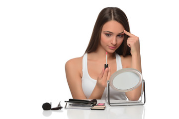  A young woman applying makeup on her face with a brush