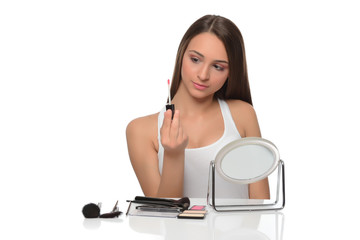  A young woman applying makeup on her face with a brush