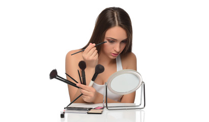  A young woman applying makeup on her face with a brush