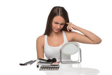  A young woman applying makeup on her face with a brush