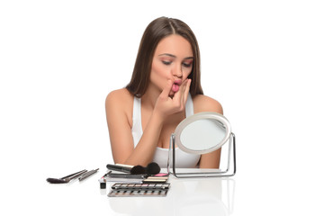  A young woman applying makeup on her face with a brush