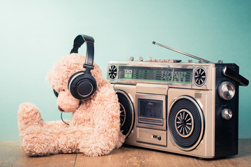 Retro radio recorder from 80s and toy Teddy Bear with headphones in front mint background. Vintage...