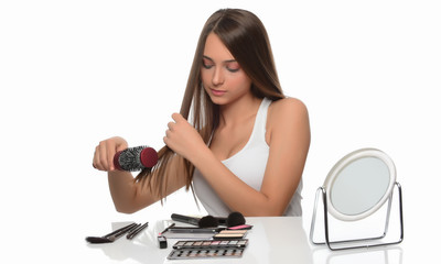 Young woman combing her hair, isolated on white background