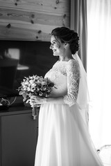 Wedding preparation. Beautiful young bride in white wedding dress indoors