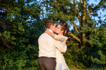 Fototapeta premium Bride and groom kissing and holding hands in the forest on nature