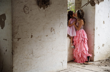 Young woman and her cute little daughter smiling, wearing a pink princess dress posing inside of an old building