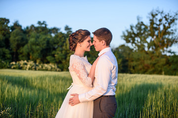 happy bride and groom kissing On the meadow near the forest on their wedding day