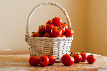 Red cherry tomatoes in a woven basket on a white background on wooden table