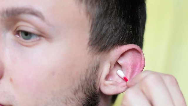 Young man cleaning ear with cotton swabs close up