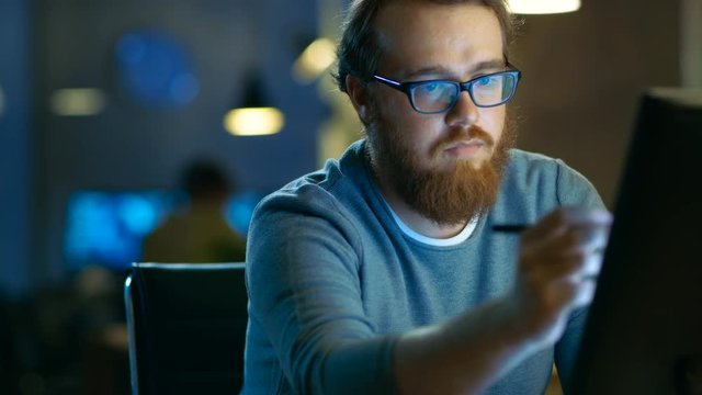 Talented Young Concept Artist Drawing on a Digital Pen Display Tablet While Sitting at His Working Place in Modern Loft Office. Late at Night. Shot on RED EPIC-W 8K Helium Cinema Camera.
