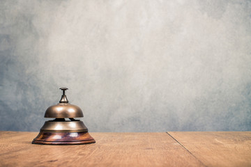 Vintage hotel reception service desk bell front textured concrete wall background. Old retro style filtered photo