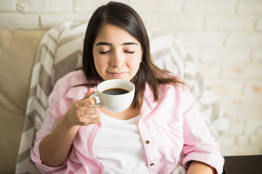 Young woman smelling freshly made coffee