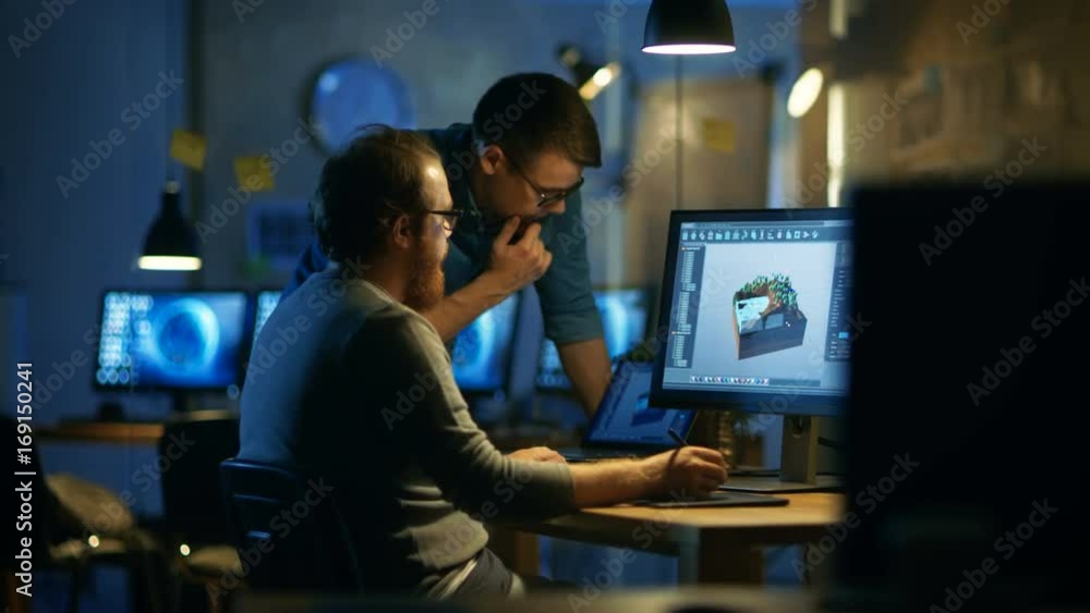 Poster two male game developers discuss game level drawing, one uses graphic tablet. they work late at nigh