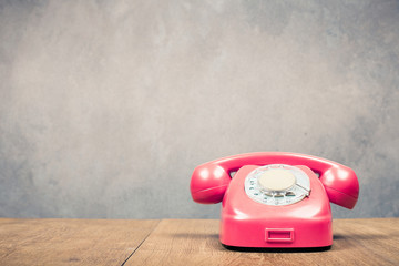 Retro old rotary telephone from 60s on table front textured concrete wall background. Vintage style...