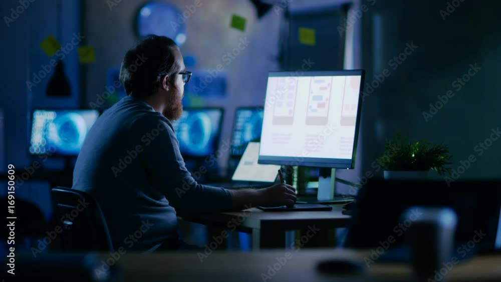 Poster Male Mobile Application Developer Works with Graphics on His Personal Computer with Two Monitors. He Works Late at Night, in an Empty Office. Shot on RED EPIC-W 8K Helium Cinema Camera.